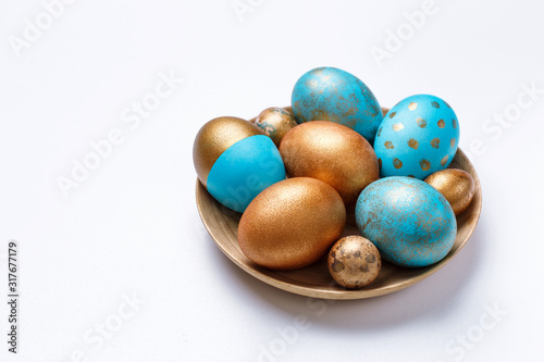 Blue and golden modern easter eggs on a wooden plate. White background.