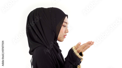 Portrait of an Asian Muslim man woman reciting Surah Al-Fatiha passage of the Qur'an in a single act of Sujud called a Sajdah or prostration in a daily prayer at home