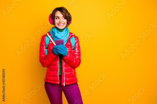 Photo of funny blogger lady walk street looking telephone screen read sms wear casual red coat blue scarf gloves ear covers pants isolated yellow color background