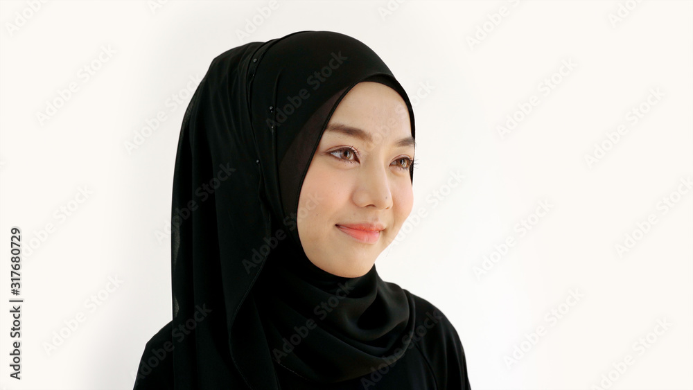 Close Up Portrait of a Young Asian Muslim Woman dressing in the traditional Hijab looking at camera smiling confident on a white background Close Up Portrait of a Young Asian Muslim Woman dressing in the traditional Hijab looking at camera smiling confident on a white background