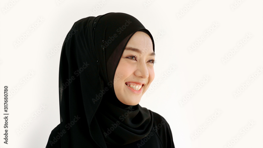 Close Up Portrait of a Young Asian Muslim Woman dressing in the traditional Hijab looking at camera smiling confident on a white background Close Up Portrait of a Young Asian Muslim Woman dressing in the traditional Hijab looking at camera smiling confident on a white background