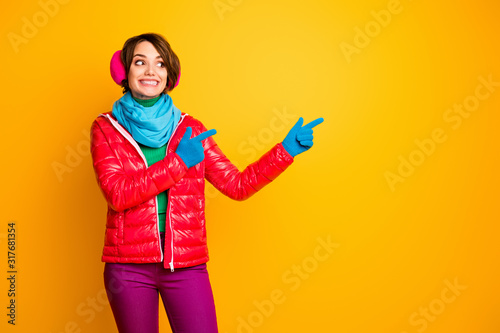 Photo of funny pretty lady indicate fingers empty space final season low prices wear casual red coat blue scarf gloves ear warmers pants isolated yellow color background