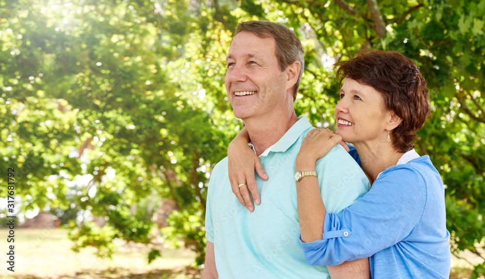 Mature husband and wife looking positively up into lush trees Mature husband and wife looking positively up into lush trees