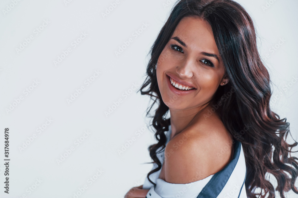 Young brunette in white coat sitting on the bed in white room Young brunette in white coat sitting on the bed in white room