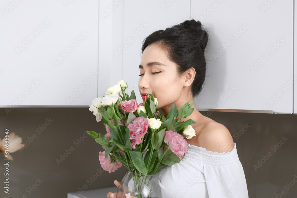 Portrait of young Asian woman with flowers in kitchen. Portrait of young Asian woman with flowers in kitchen.