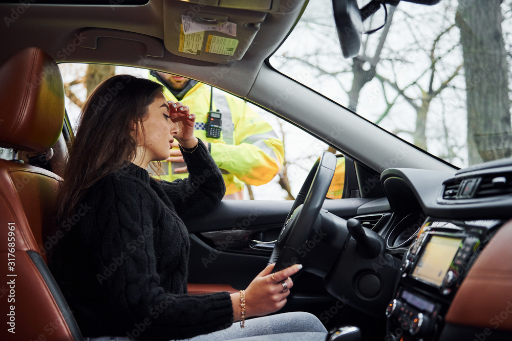 Naklejka premium Girls feels bad. Male police officer in green uniform checking vehicle on the road