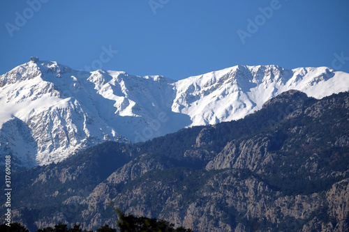 Landscape with Turkish mountains of different heights, mountain pines on the slopes and snow on high peaks at far