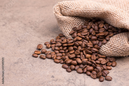 Roasted coffee beans on a brown textured stone background, empty copy space for text © Berit Kessler