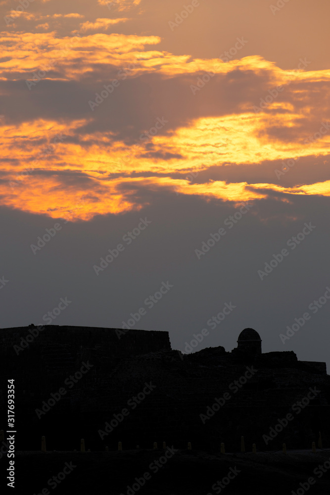 Silhouette of ancient Bahrain Fort watch tower during sunset