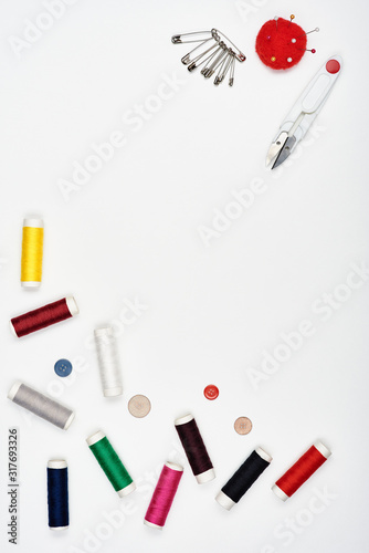 Colored threads and sewing accessories on a white background.