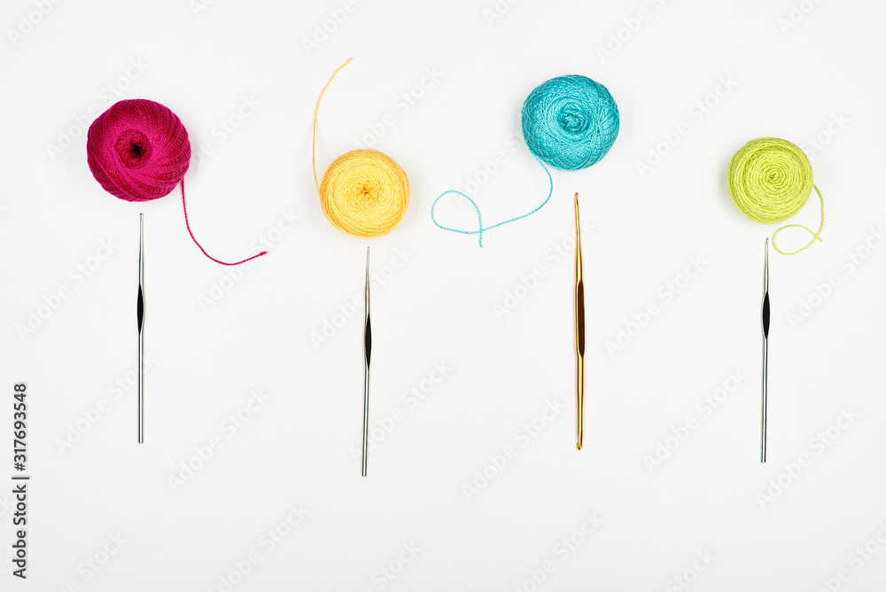 Composition with colorful threads and crochet hooks. White background. Top view. Composition with colorful threads and crochet hooks. White background. Top view.