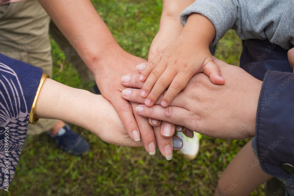 Close-up top view of young people and kid putting their hands together. Family with stack of hands showing unity and teamwork. Close-up top view of young people and kid putting their hands together. Family with stack of hands showing unity and teamwork.