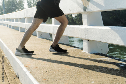 Strong man legs stretching before fitness/running on the bridge in the summer. Close up only the legs.Sports concept. Healthy lifestyle. © sorawat