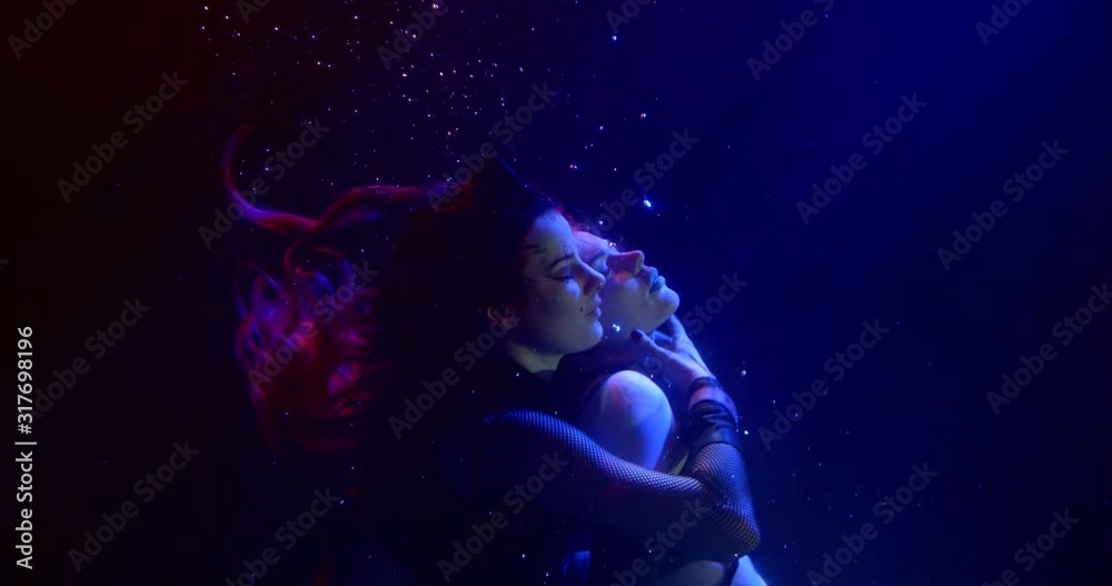 Two fateful Sexy Girls with long hair are in the Studio under water on a blue background. They are lesbians, hugging and touching each other. Their hair is flying. They wear short tops and shorts. Two fateful Sexy Girls with long hair are in the Studio under water on a blue background. They are lesbians, hugging and touching each other. Their hair is flying. They wear short tops and shorts.
