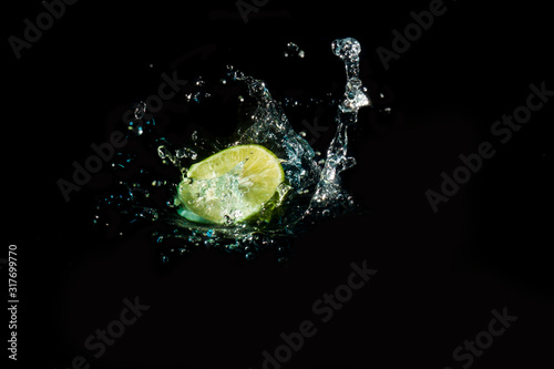 Lemon slice into the water until the sponge splits beautifully on a black background.
