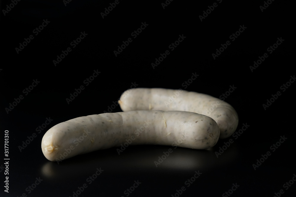 Two long white raw bratwurst sausage isolated on black background Two long white raw bratwurst sausage isolated on black background