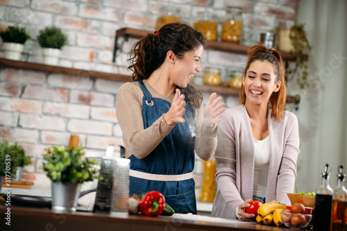 Two friends having fun in kitchen. Sisters cooking together.