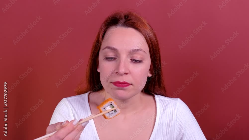 Portrait Redhead Young woman eating sushi with chopsticks. Portrait Redhead Young woman eating sushi with chopsticks.