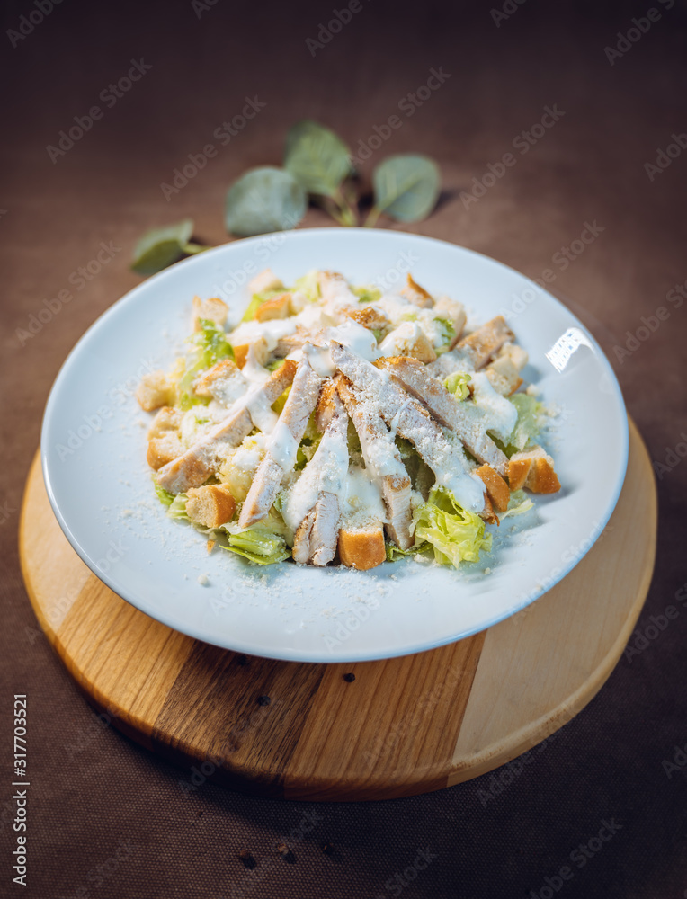 Cesar salad with cheese, chicken, bread, spices on wooden plate from above Cesar salad with cheese, chicken, bread, spices on wooden plate from above