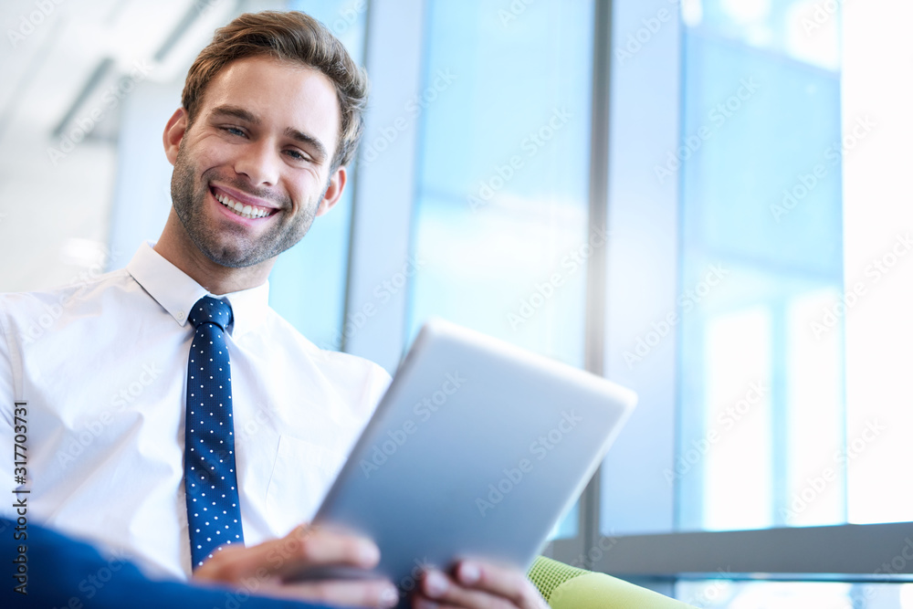 Friendly businessman smiling while holding a digital tablet Friendly businessman smiling while holding a digital tablet