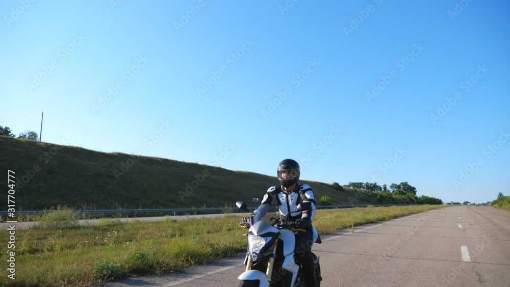 Man in helmet riding fast on sport motorbike at highway. Motorcyclist racing his motorcycle against scenic nature view. Guy in protective equipment enjoying trip. Adventure or freedom concept. Slow mo