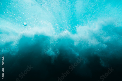 Wave with bubbles underwater. Transparent blue ocean in underwater