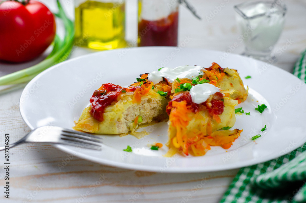 Homemade cabbage rolls with carrots, red tomato sauce and cream on a white plate Homemade cabbage rolls with carrots, red tomato sauce and cream on a white plate
