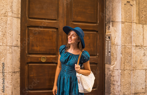 Young and beautiful brunette girl in dress and hat walking outdoor in the street. Nice, France. Summer vacation, traveling and tourism. © Acronym