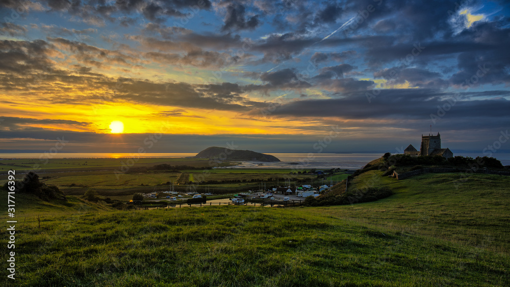 A beautiful sunset on the Bristol Channel in Somerset near the town of Weston-Super-Mare. Colorful clouds and green hills in the south of England. In the background is the sea.