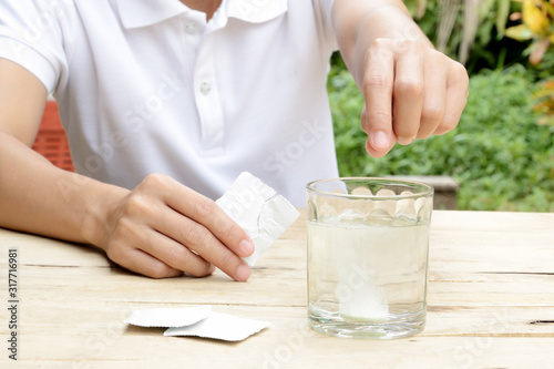 woman dropping effervescent tablet in glass of water