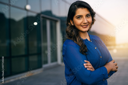 Confident young businesswoman standing on an office balcony at dusk