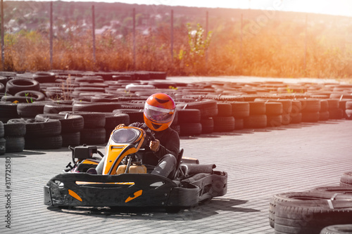 A driver in gear and helmet drives a racing car. In action. Go karts racing, sreet karting, rent. extreme sport. fun entertainment for drivers. Soft light glow, copy space