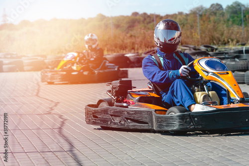 A driver in gear and helmet drives a racing car. In action. Go karts racing, sreet karting, rent. extreme sport. fun entertainment for drivers. Soft light glow, copy space