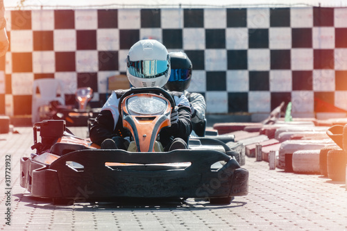 Equipped drivers are sitting in a racing car. Ready for battle, championship. Go karts racing, sreet extreme sport. fun entertainment for drivers, black and white race flag on background photo