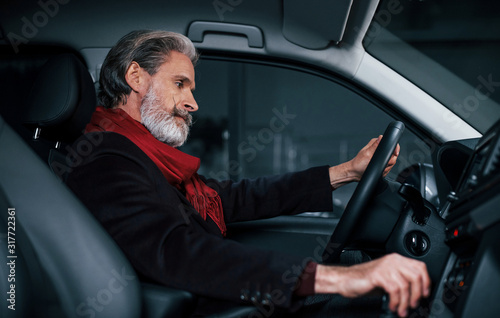 Side view of modern stylish senior man with grey hair that is in the modern car © standret
