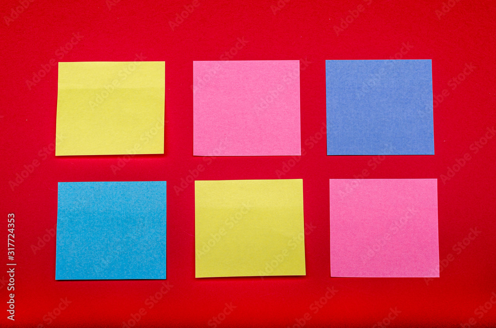 some coulored sticky notes on a red background