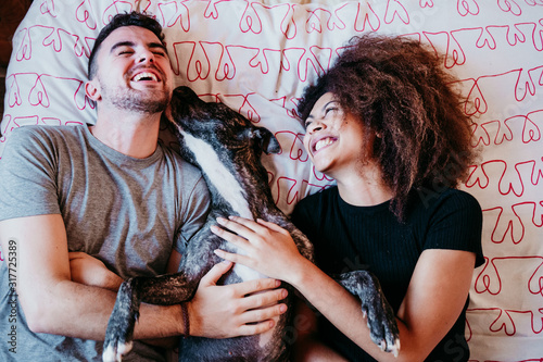 happy couple in love at home. Afro american woman, caucasian man and their pit bull dog together. Family concept