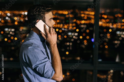 Young businessman talking on a cellphone late at night