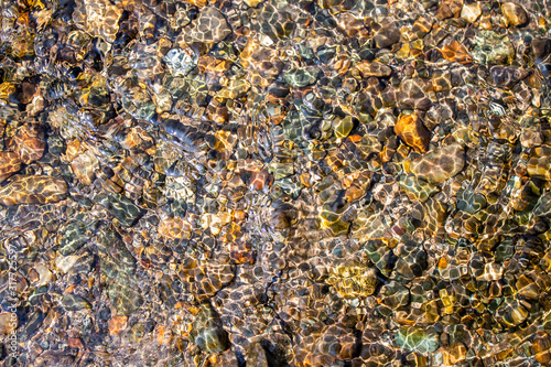 Colorful pebbles under water in a river for background