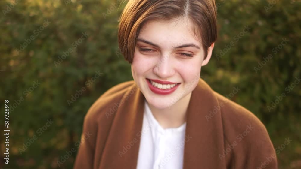Close portrait of a beautiful young girl with a short haircut and a white-toothed smile. Happy woman, outdoor portrait Close portrait of a beautiful young girl with a short haircut and a white-toothed smile. Happy woman, outdoor portrait