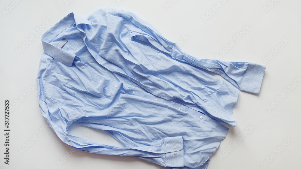 Blue cotton wrinkled and rumpled shirt on white. Washed shirt after tumble dryer