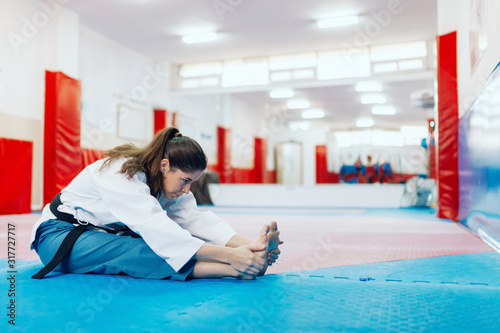 Young woman stretching in a dojo wearing taekwondo suit photo