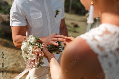 Marriage hands with rings. Bride wears the ring on the finger of the groom. Wedding cermony outdoor photo