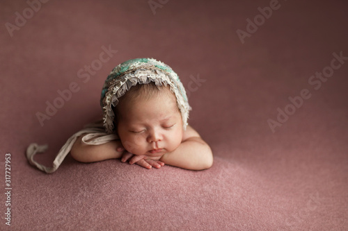 Lovely newborn baby girl laying on her belly. Little girl in a hat.