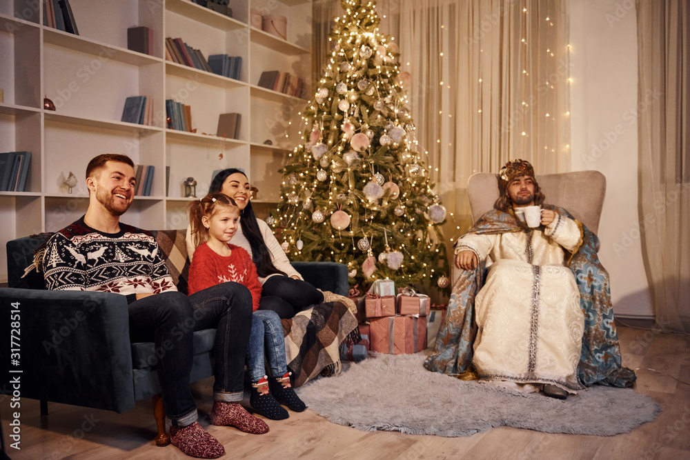 Happy family with guy in saint clothes celebrating new year in christmas decorated room