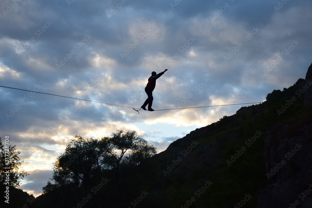 Practicing highline sports between rocky mountains, walking on a thin line Practicing highline sports between rocky mountains, walking on a thin line