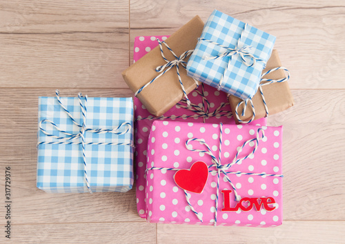 Valentine's day background. Cute composition with handmade gift boxes and red hearts on wooden table. Happy birthday or anniversary congratulation.
