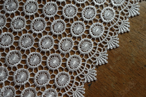 Edge of ivory white crochet lace on wooden table