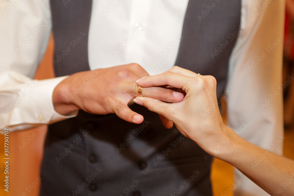 bride puts on a wedding ring to the groom