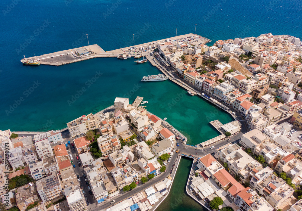 Top view of a European city and a ship off the coast of the Mediterranean Sea, in the frame a bridge over the lake and the roofs of buildings. Aerial photography, Crete, Greece